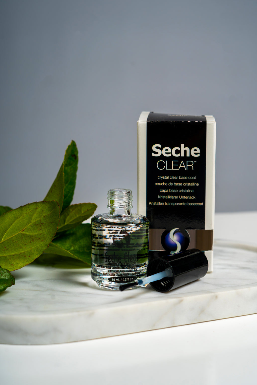 Seche Clear Crystal Clear Base Coat bottle and box on a marble tray with green leaves